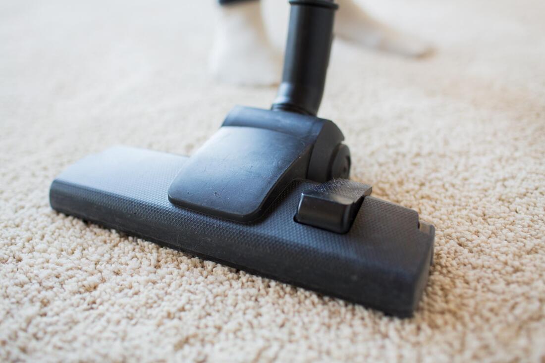 someone is cleaning the carpet using a  vacuum